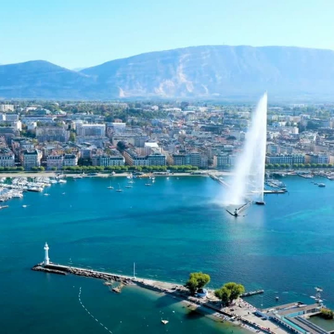 Aerial view of Lake Geneva and the city skyline featuring the Jet d'Eau water jet.